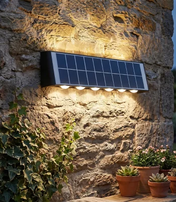 Aplică LED de exterior cu panou solar montată pe perete de piatră, iluminând grădina cu lumină caldă