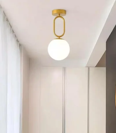 Lustră aurie glob sticlă albă montată pe tavan într-un hol modern