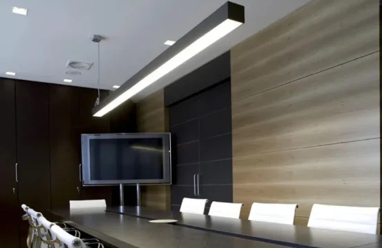 Corp LED liniar negru suspendat deasupra unei mese de conferință moderne